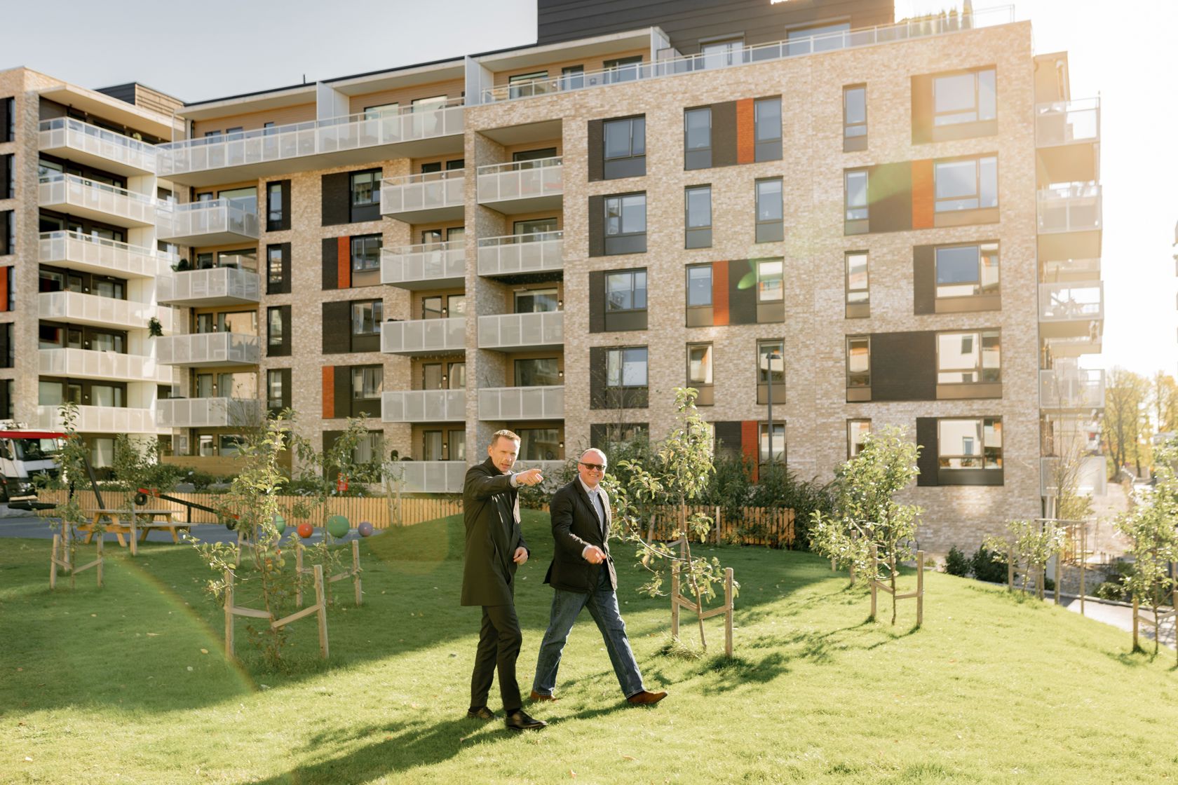 To menn som går foran en ny boligblokk på Grefsen