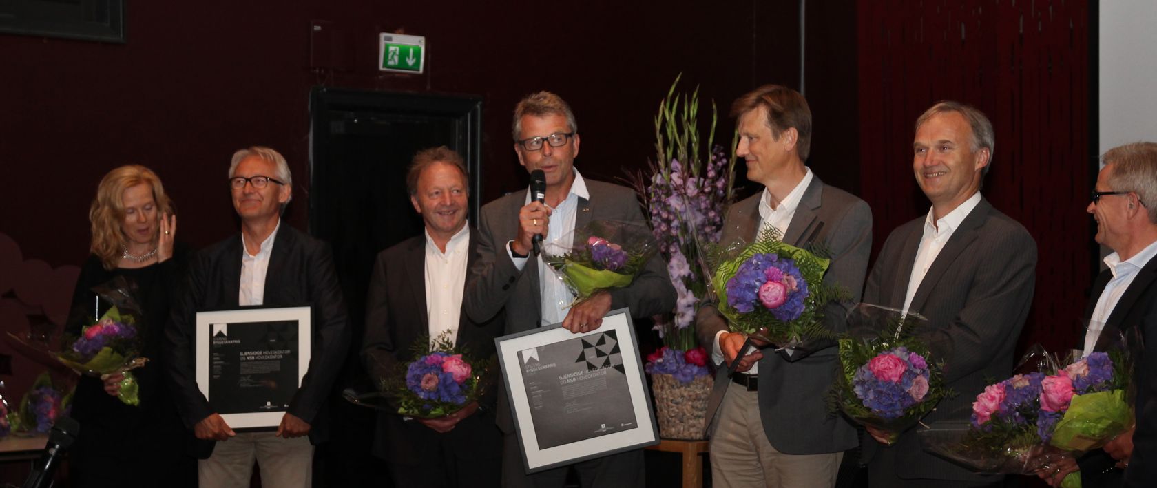 Fem mann på scenen for å motta pris og blomster