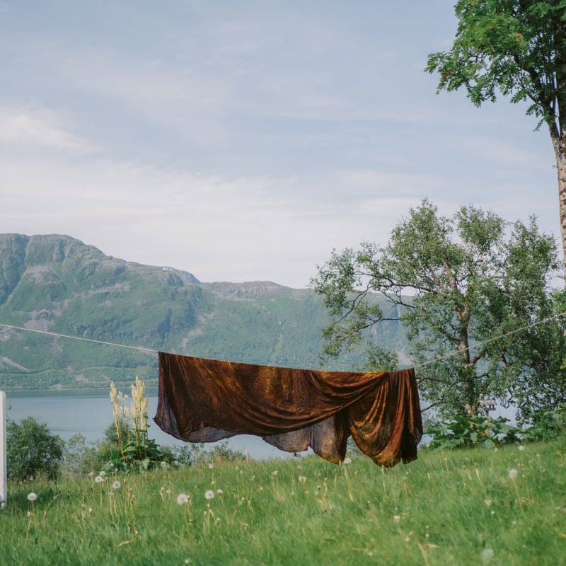 Fjell og fjord og en tørkesnor med et brunt ullpledd hengende over.