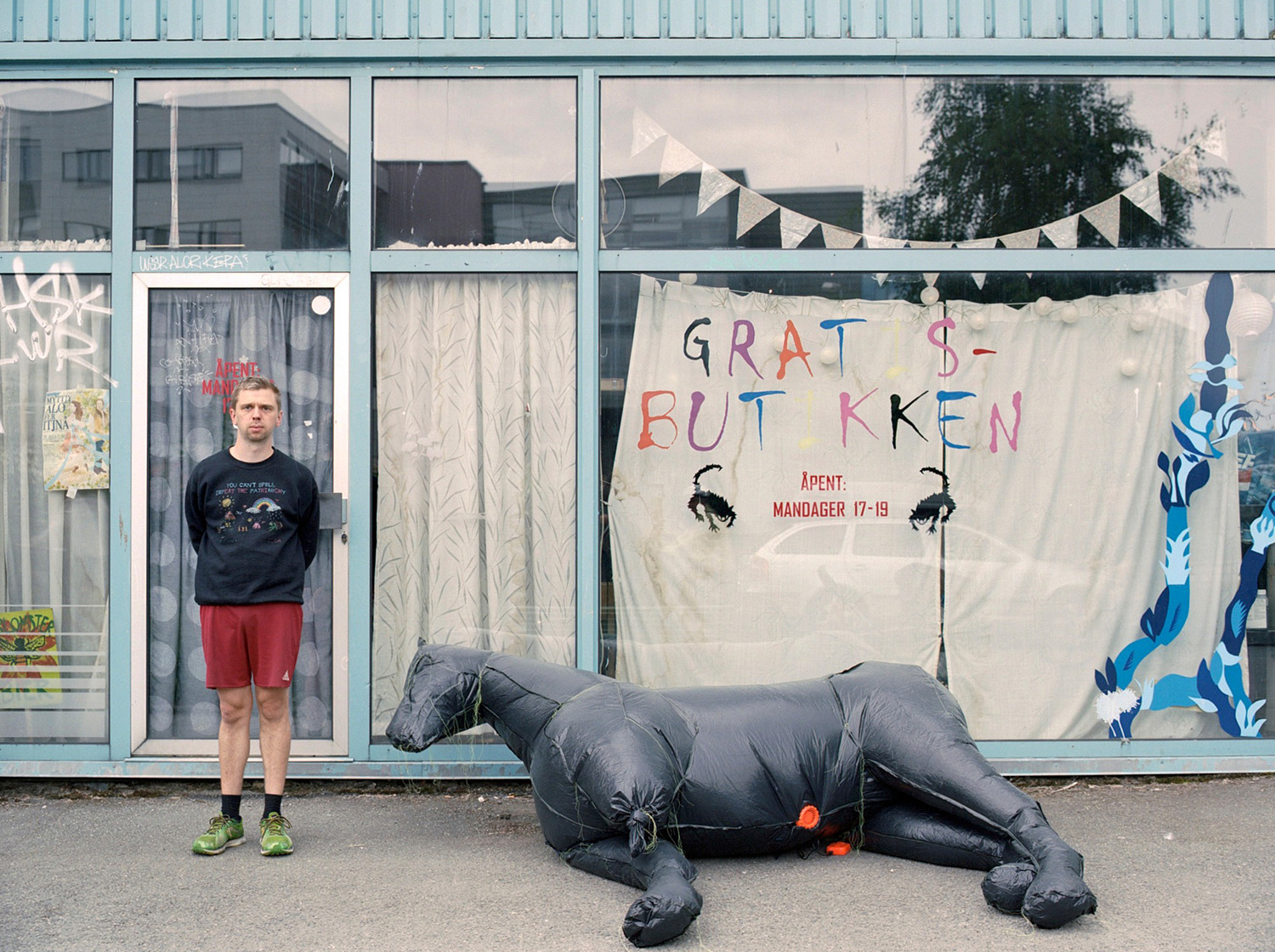 Kunstneren med en hestelignende skulptur foran en butikkfasade.