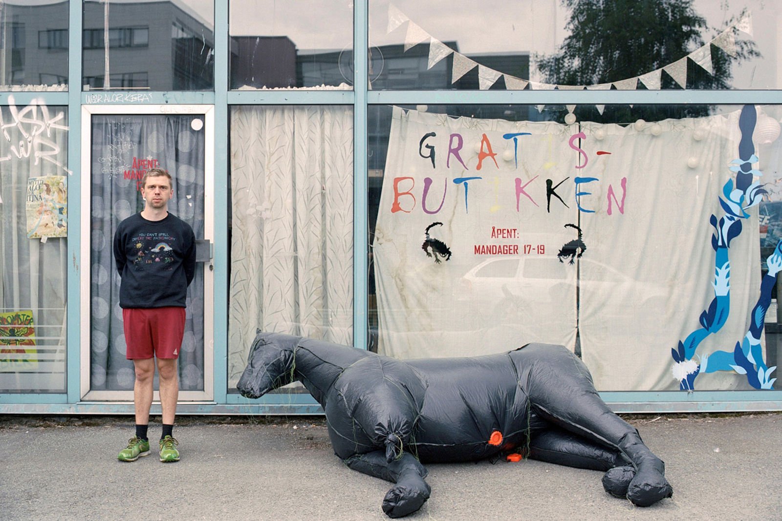 Kunstneren med en hestelignende skulptur foran en butikkfasade.