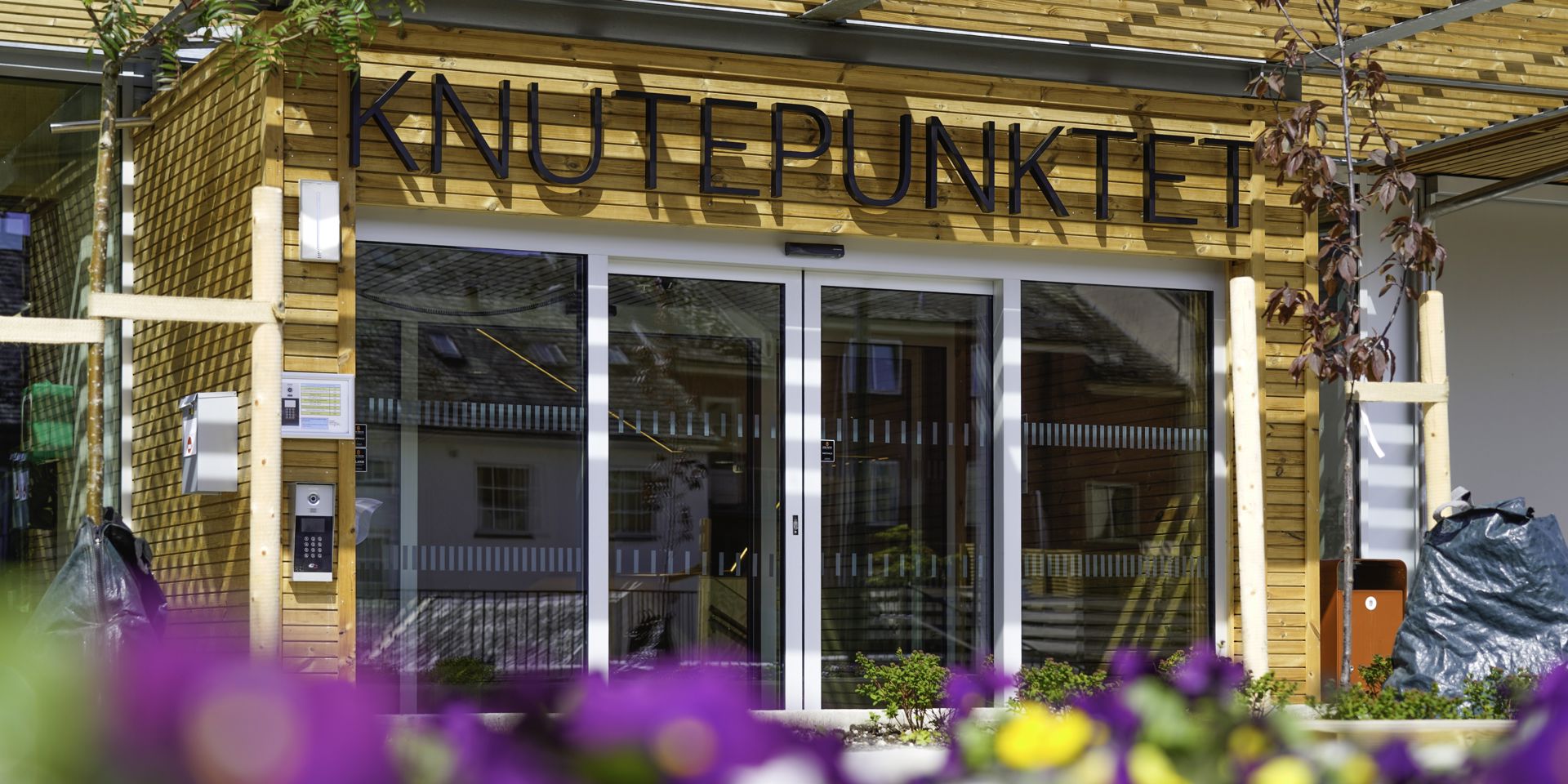 Inngangspartiet til Knutepunktet med sommerblomster i forkant.