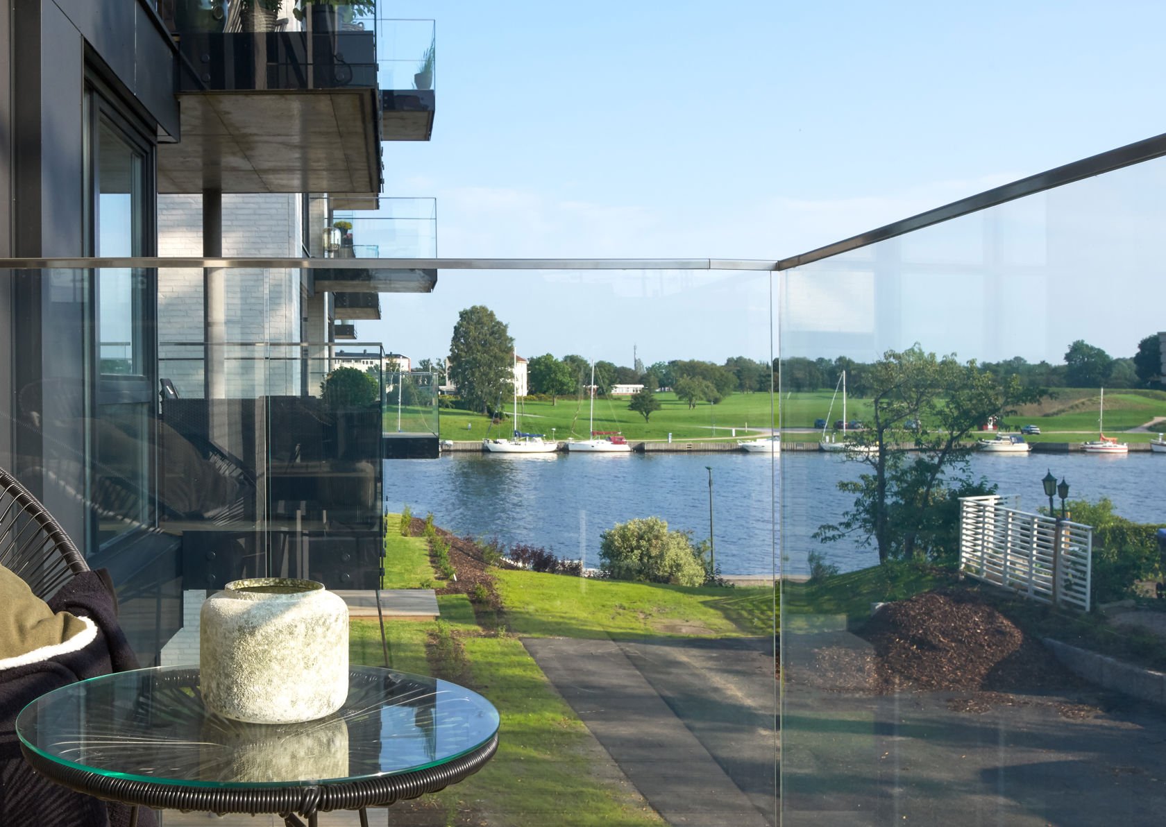 Utsikt fra innglasset terrasse mot grøntarealer og Glomma.