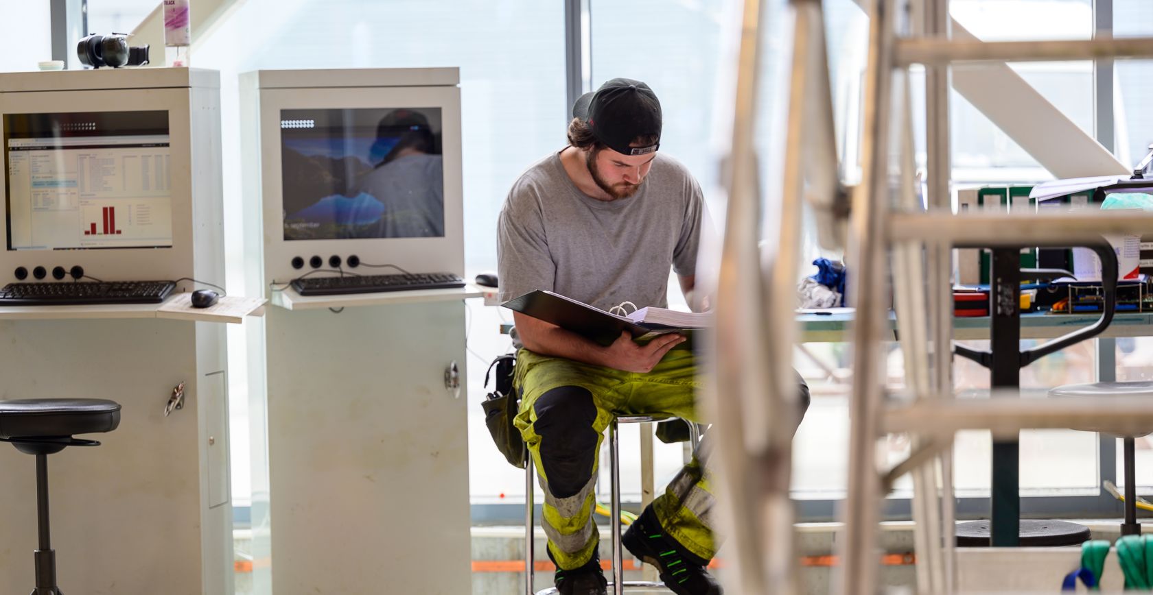 En driftsteknikker som sitter å jobber