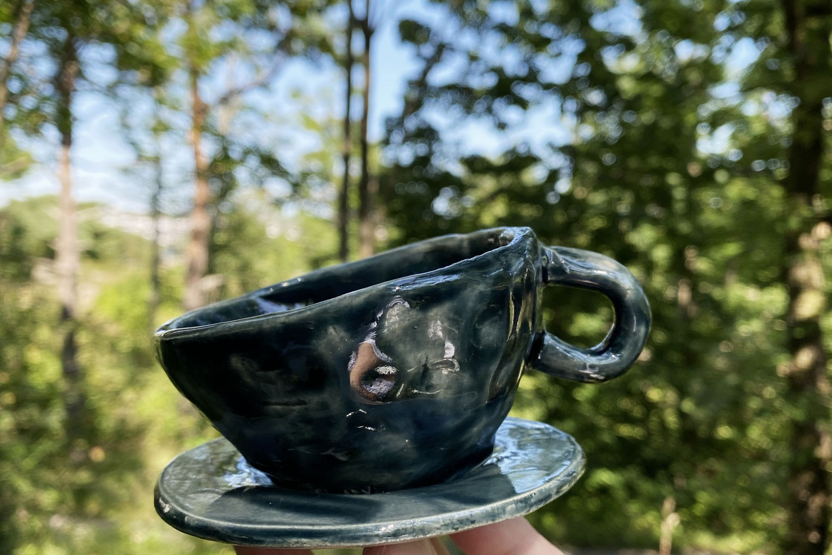 Hånd holder en kopp i skogen