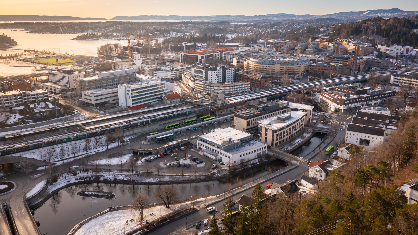 Dronebilde av by med jernbanestasjon og jernbanespor