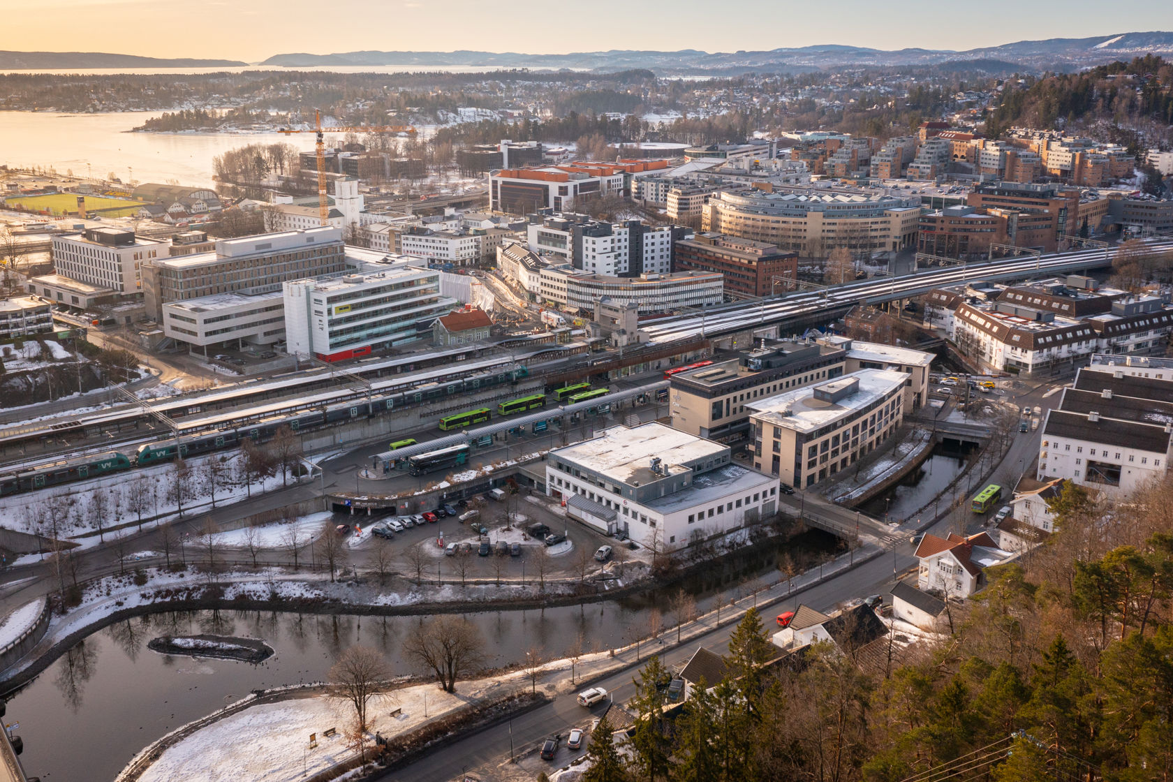 Dronebilde av by med jernbanestasjon og jernbanespor