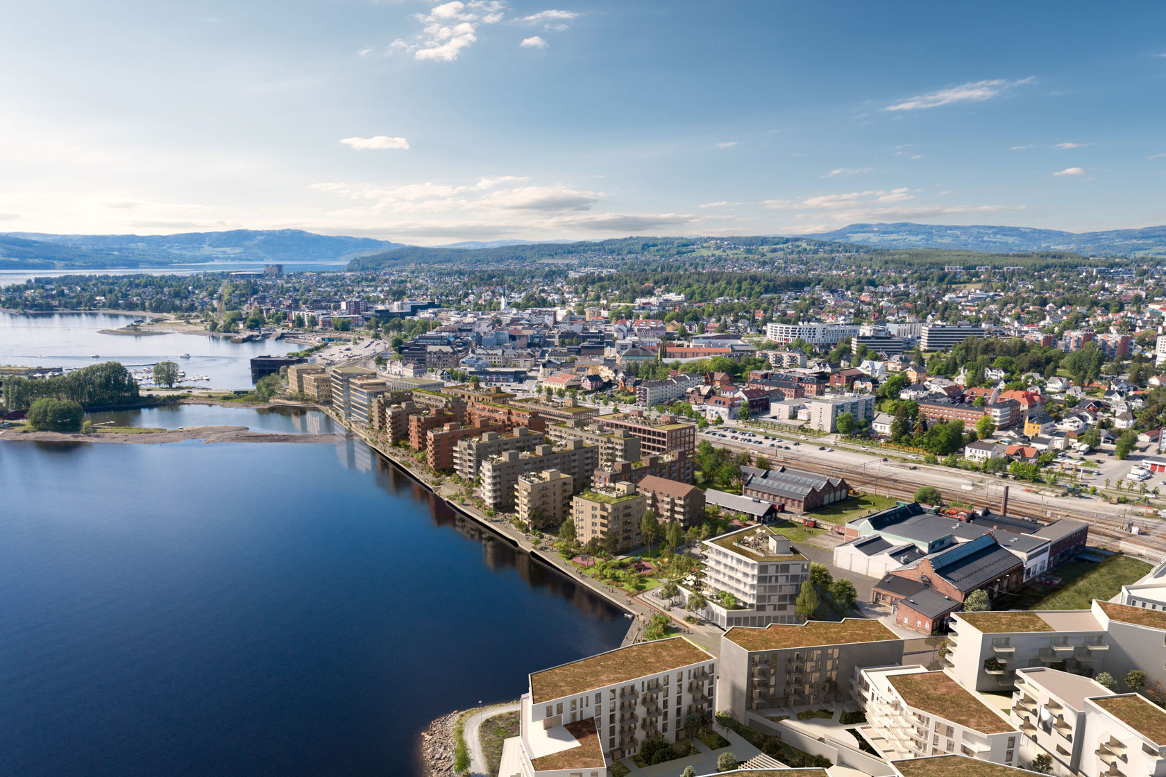 dronebilde med illustrasjoner av nye bygg ved sjøkanten av Mjøsa. Like ved stasjonen.